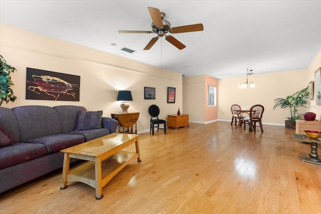 living room with light hardwood / wood-style floors and ceiling fan with notable chandelier