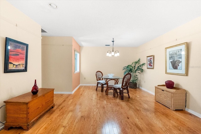 dining room featuring light wood-type flooring and an inviting chandelier