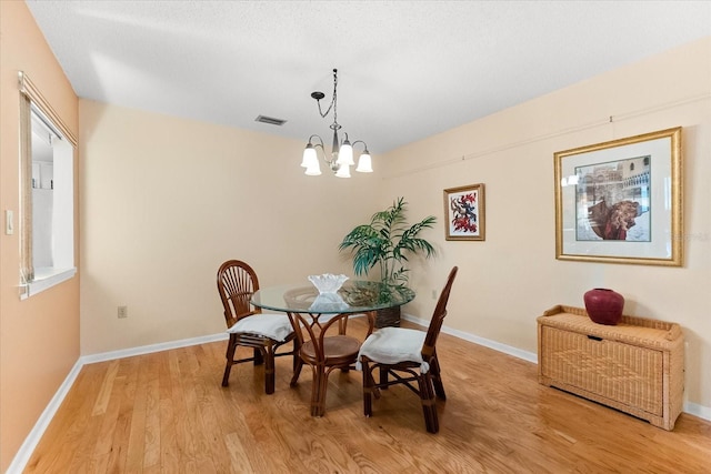 dining area featuring a chandelier, a textured ceiling, and light hardwood / wood-style flooring