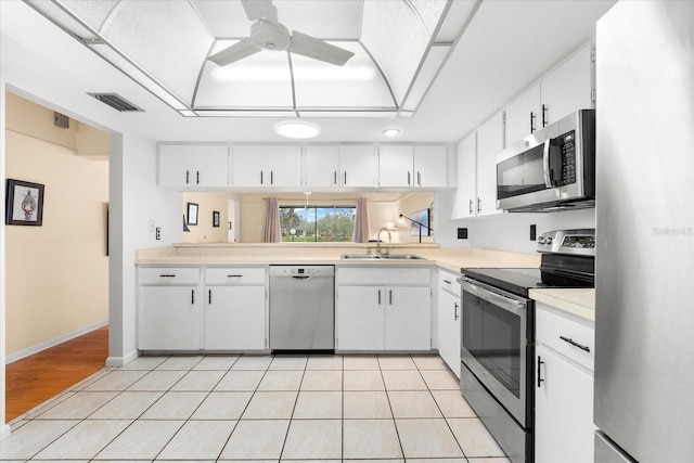 kitchen featuring appliances with stainless steel finishes, sink, light tile patterned floors, and white cabinets