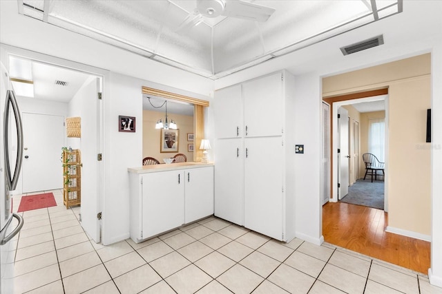 kitchen featuring stainless steel fridge, hanging light fixtures, light hardwood / wood-style floors, white cabinets, and ceiling fan