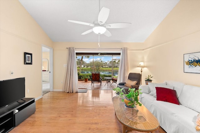 living room featuring ceiling fan, light wood-type flooring, and vaulted ceiling