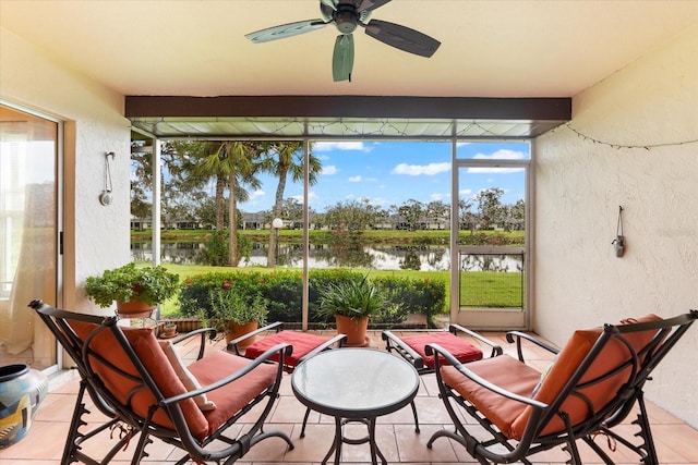 sunroom with ceiling fan, a water view, a healthy amount of sunlight, and beam ceiling