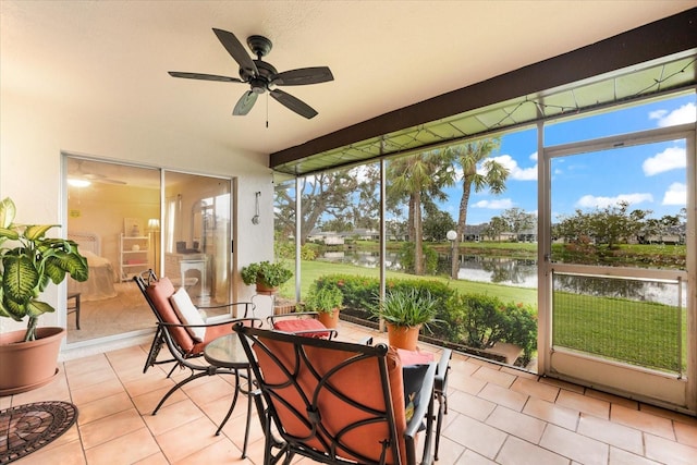 sunroom with ceiling fan and a water view