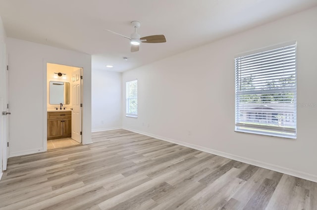 unfurnished bedroom featuring ceiling fan, light wood-type flooring, sink, and connected bathroom