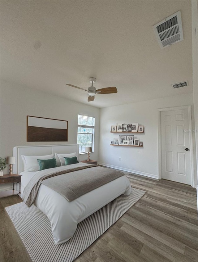 bedroom featuring ceiling fan, hardwood / wood-style floors, and a textured ceiling