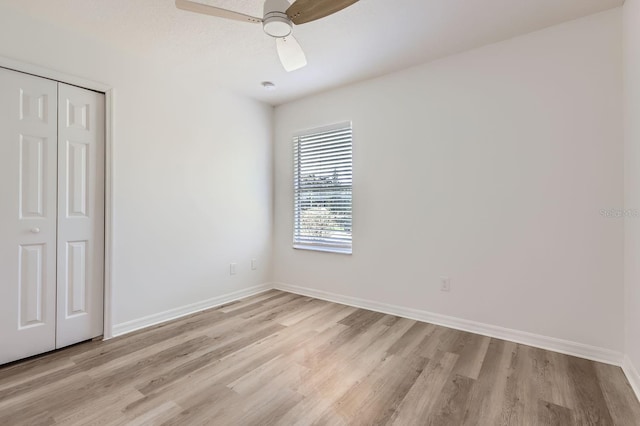 unfurnished bedroom featuring ceiling fan, light hardwood / wood-style floors, and a closet