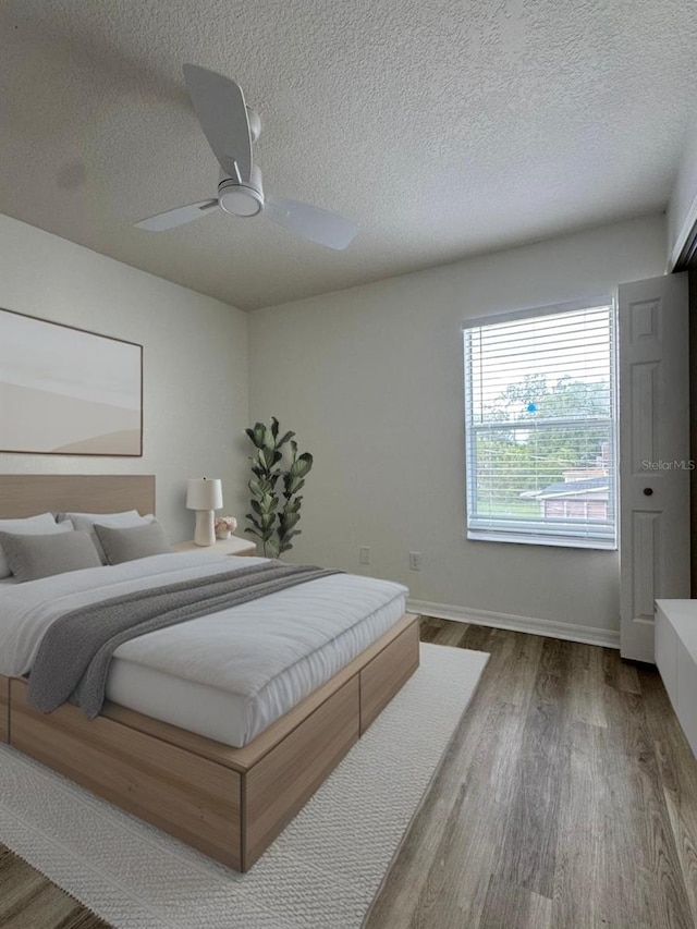 bedroom featuring hardwood / wood-style flooring, ceiling fan, and a textured ceiling