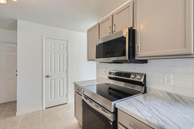 kitchen featuring gray cabinets, decorative backsplash, light tile patterned flooring, and stainless steel appliances