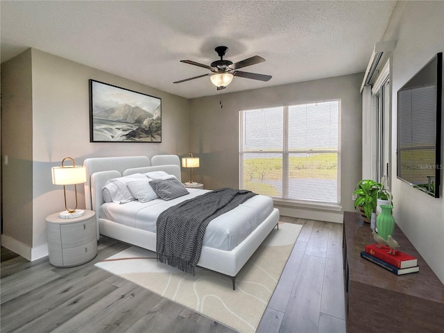 bedroom with ceiling fan, wood-type flooring, and a textured ceiling