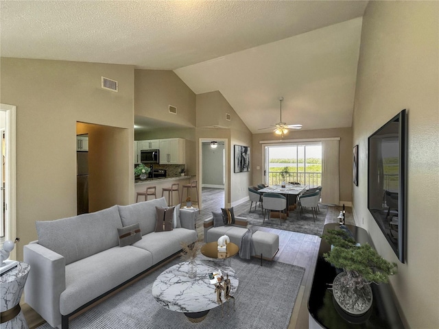 living room with dark hardwood / wood-style flooring, a textured ceiling, vaulted ceiling, and ceiling fan