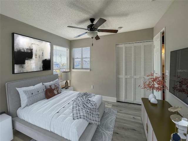 bedroom featuring ceiling fan, light wood-type flooring, a textured ceiling, and a closet