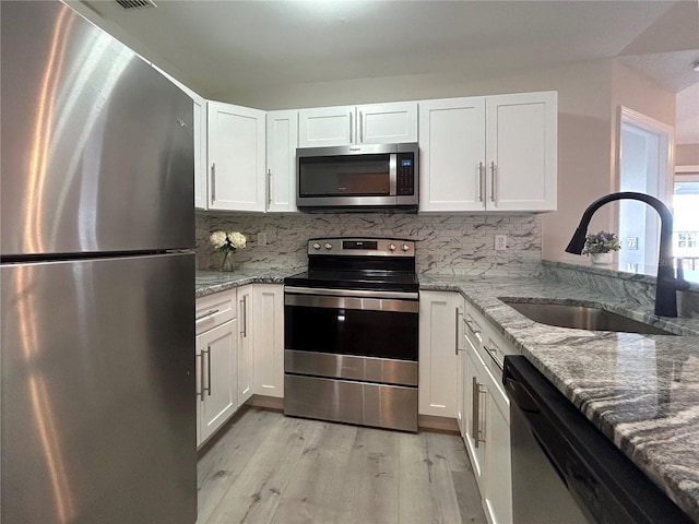 kitchen featuring light stone counters, white cabinetry, sink, and appliances with stainless steel finishes