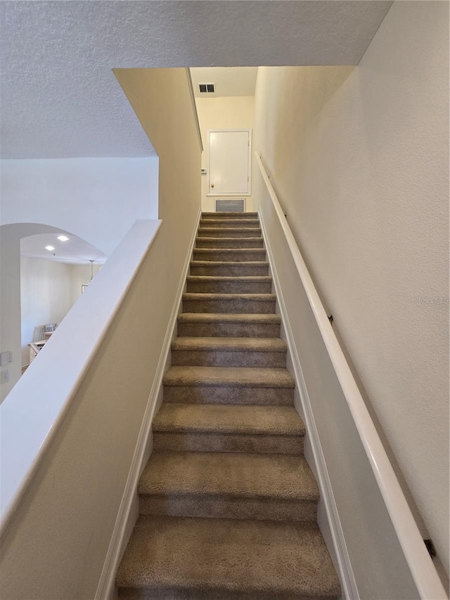 stairway featuring a textured ceiling