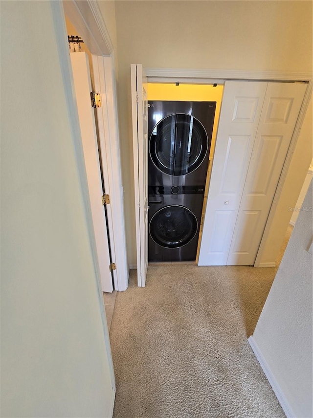 clothes washing area featuring light carpet and stacked washer and clothes dryer