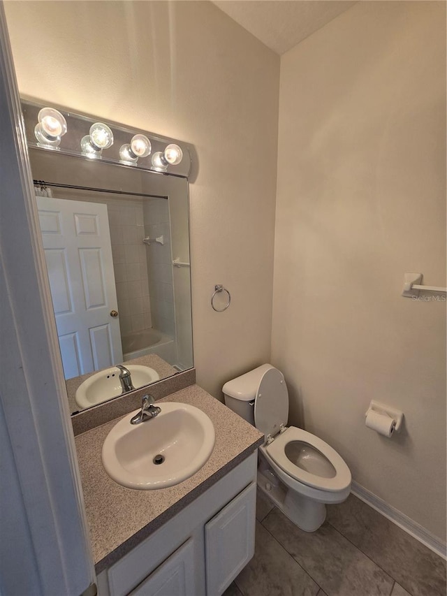 bathroom with toilet, vanity, and tile patterned flooring