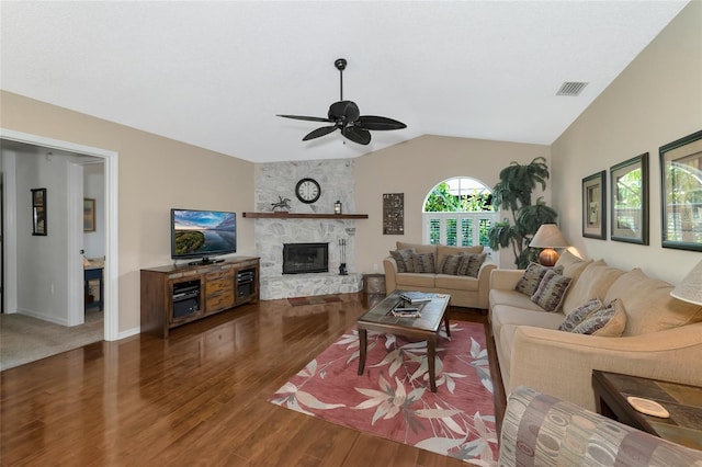 living room featuring ceiling fan, a large fireplace, dark wood-type flooring, and vaulted ceiling