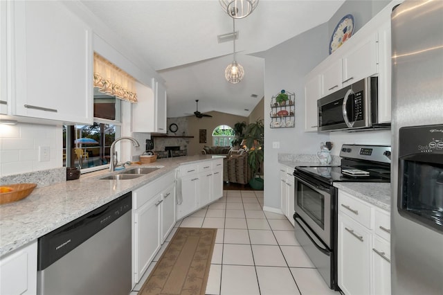 kitchen with lofted ceiling, white cabinets, sink, decorative light fixtures, and stainless steel appliances