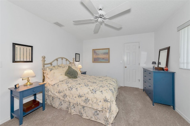 carpeted bedroom with ceiling fan and a textured ceiling