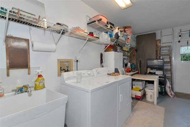 clothes washing area featuring washer and clothes dryer, sink, and a textured ceiling