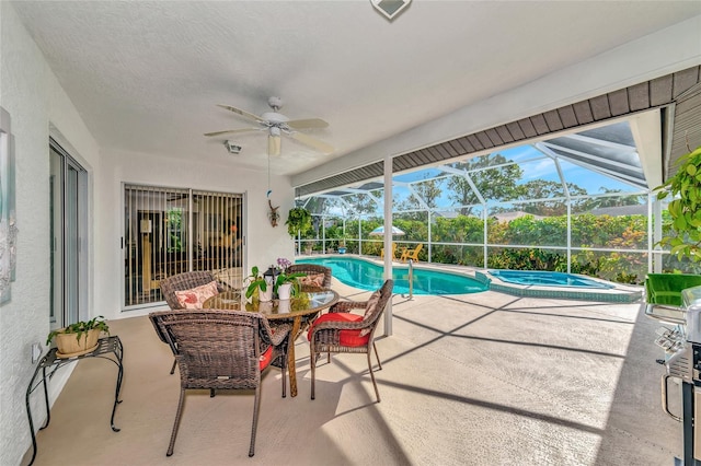 view of swimming pool featuring an in ground hot tub, a patio, glass enclosure, and ceiling fan