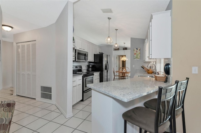 kitchen with kitchen peninsula, stainless steel appliances, pendant lighting, light tile patterned floors, and white cabinets