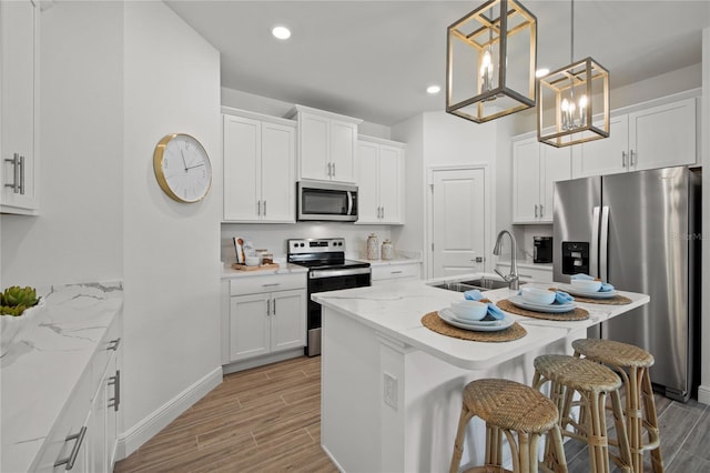 kitchen with white cabinetry, stainless steel appliances, sink, and an island with sink