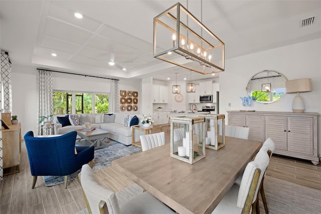 dining space featuring light hardwood / wood-style floors and coffered ceiling