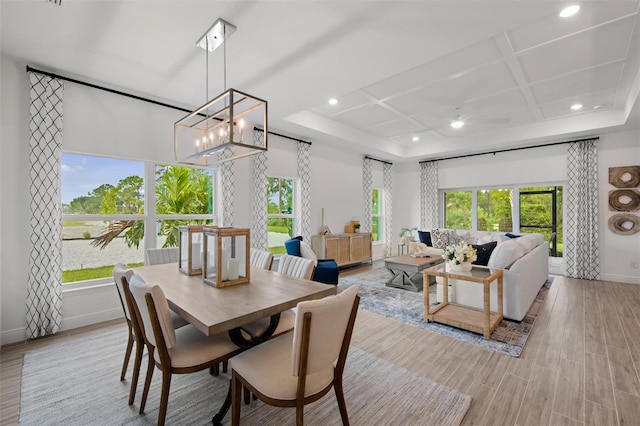 dining area with a chandelier, light hardwood / wood-style flooring, and coffered ceiling