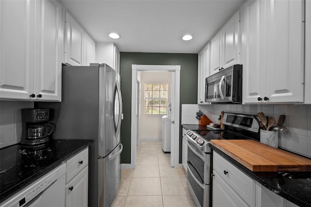 kitchen with dark stone countertops, white cabinetry, appliances with stainless steel finishes, and light tile patterned floors