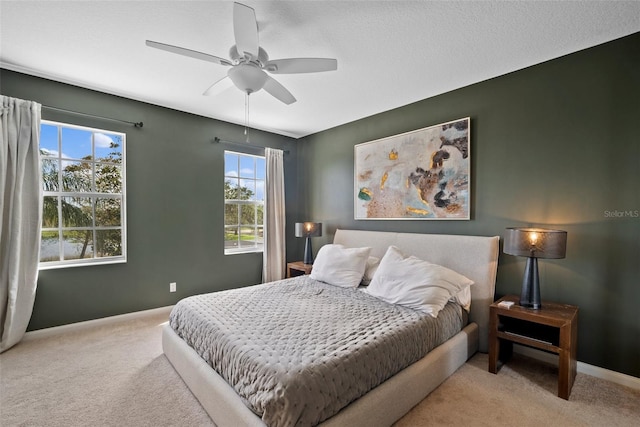 carpeted bedroom featuring multiple windows, a textured ceiling, and ceiling fan