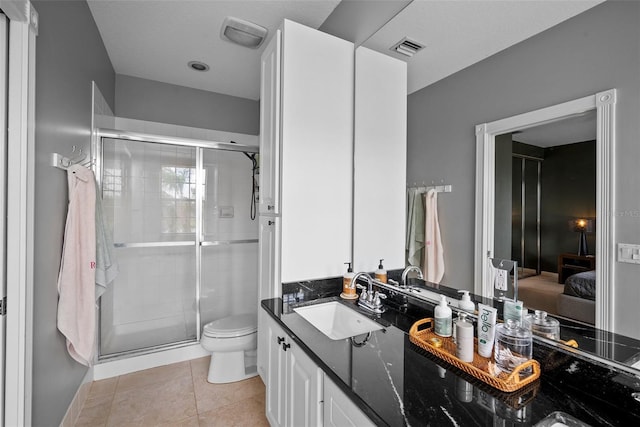 bathroom featuring vanity, a shower with door, tile patterned flooring, and toilet