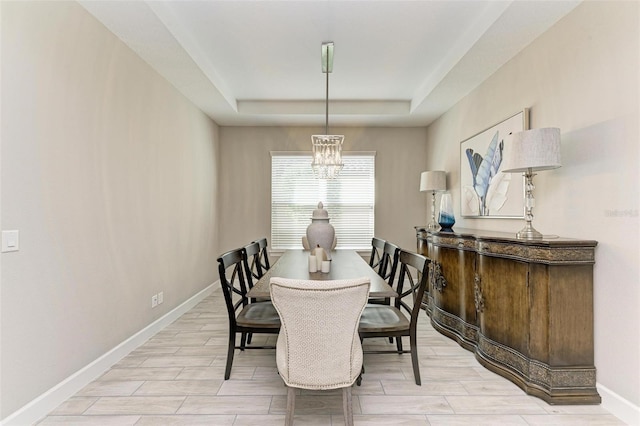 dining room featuring an inviting chandelier, a raised ceiling, and light wood-type flooring