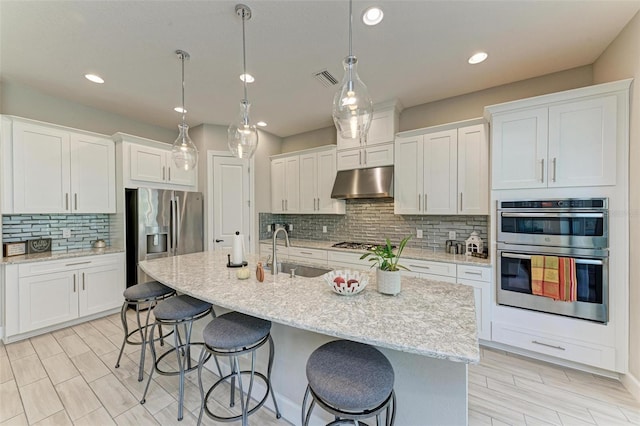 kitchen featuring white cabinets, a center island with sink, appliances with stainless steel finishes, and sink