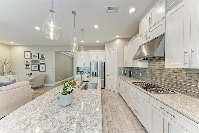 kitchen featuring stainless steel appliances, decorative backsplash, sink, white cabinetry, and decorative light fixtures