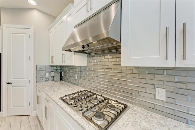 kitchen featuring white cabinets, stainless steel gas cooktop, backsplash, and light stone countertops