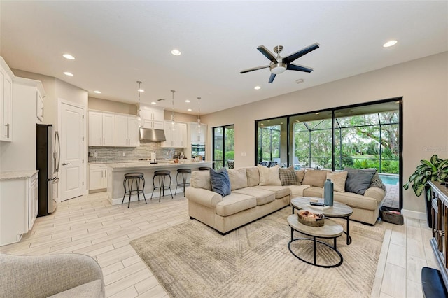 living room with ceiling fan, plenty of natural light, and light hardwood / wood-style flooring