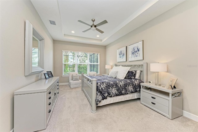 bedroom with light colored carpet, ceiling fan, and a raised ceiling