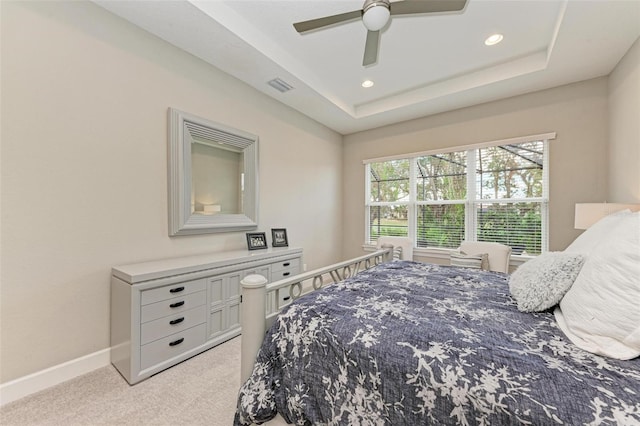 carpeted bedroom with ceiling fan and a raised ceiling