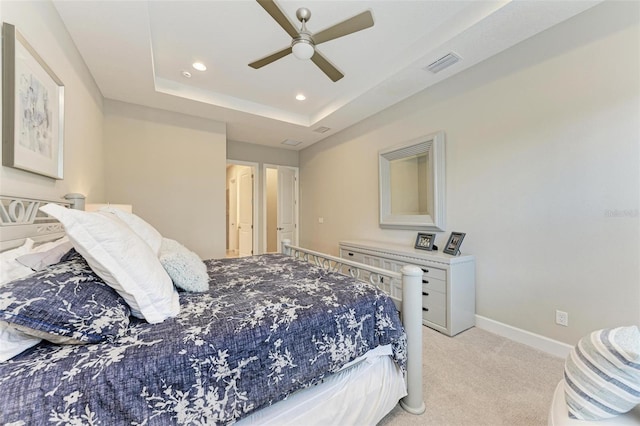 bedroom with light colored carpet, ceiling fan, and a raised ceiling