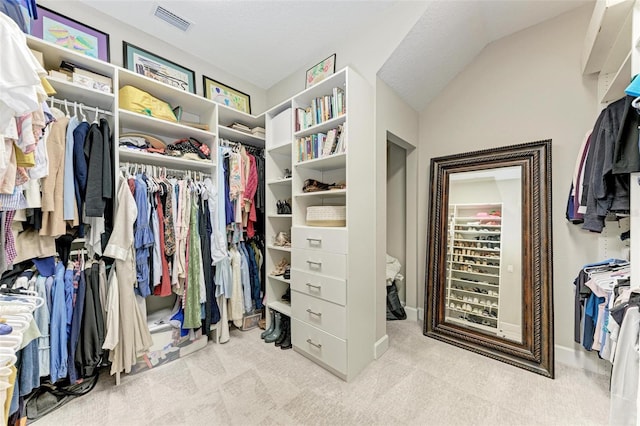 spacious closet with lofted ceiling and light carpet