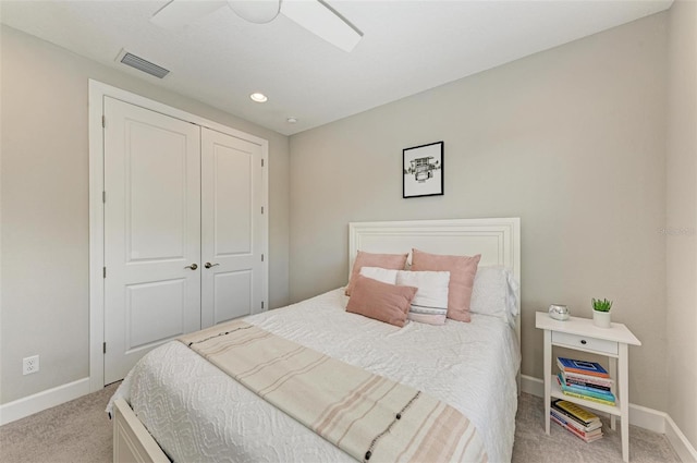 bedroom with ceiling fan, light carpet, and a closet