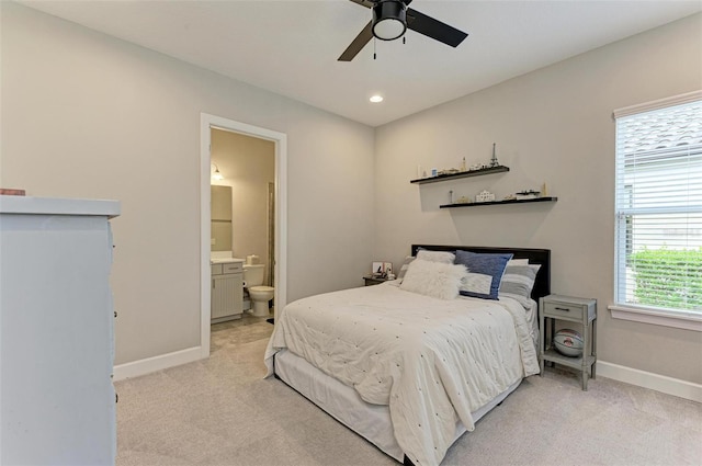 bedroom featuring ensuite bathroom, light colored carpet, and ceiling fan