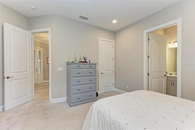 bedroom featuring light colored carpet and ensuite bathroom