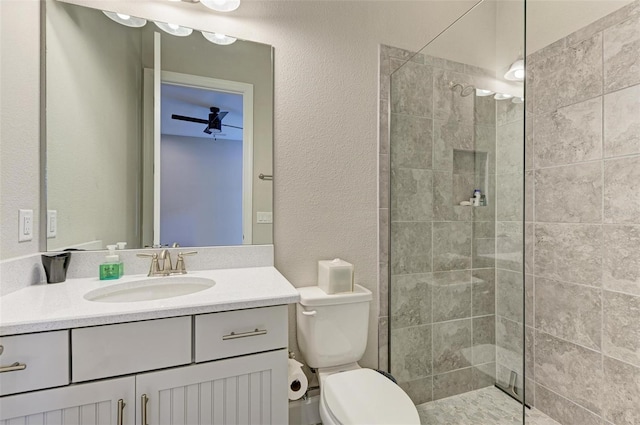 bathroom with a tile shower, vanity, and toilet