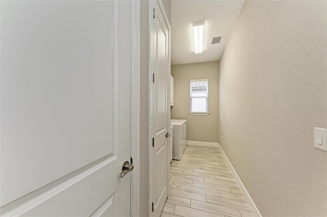 corridor featuring washing machine and clothes dryer and light hardwood / wood-style floors