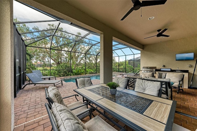 view of patio / terrace featuring a grill, glass enclosure, ceiling fan, and exterior kitchen