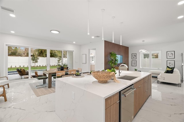 kitchen featuring hanging light fixtures, sink, a kitchen island with sink, and dishwasher