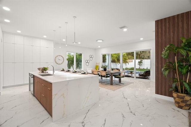 kitchen with dishwasher, sink, a kitchen island with sink, white cabinetry, and decorative light fixtures