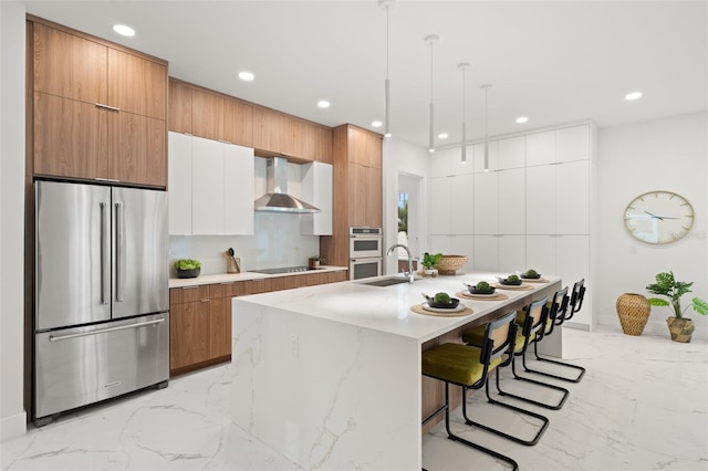 kitchen with white cabinets, stainless steel appliances, pendant lighting, and wall chimney range hood